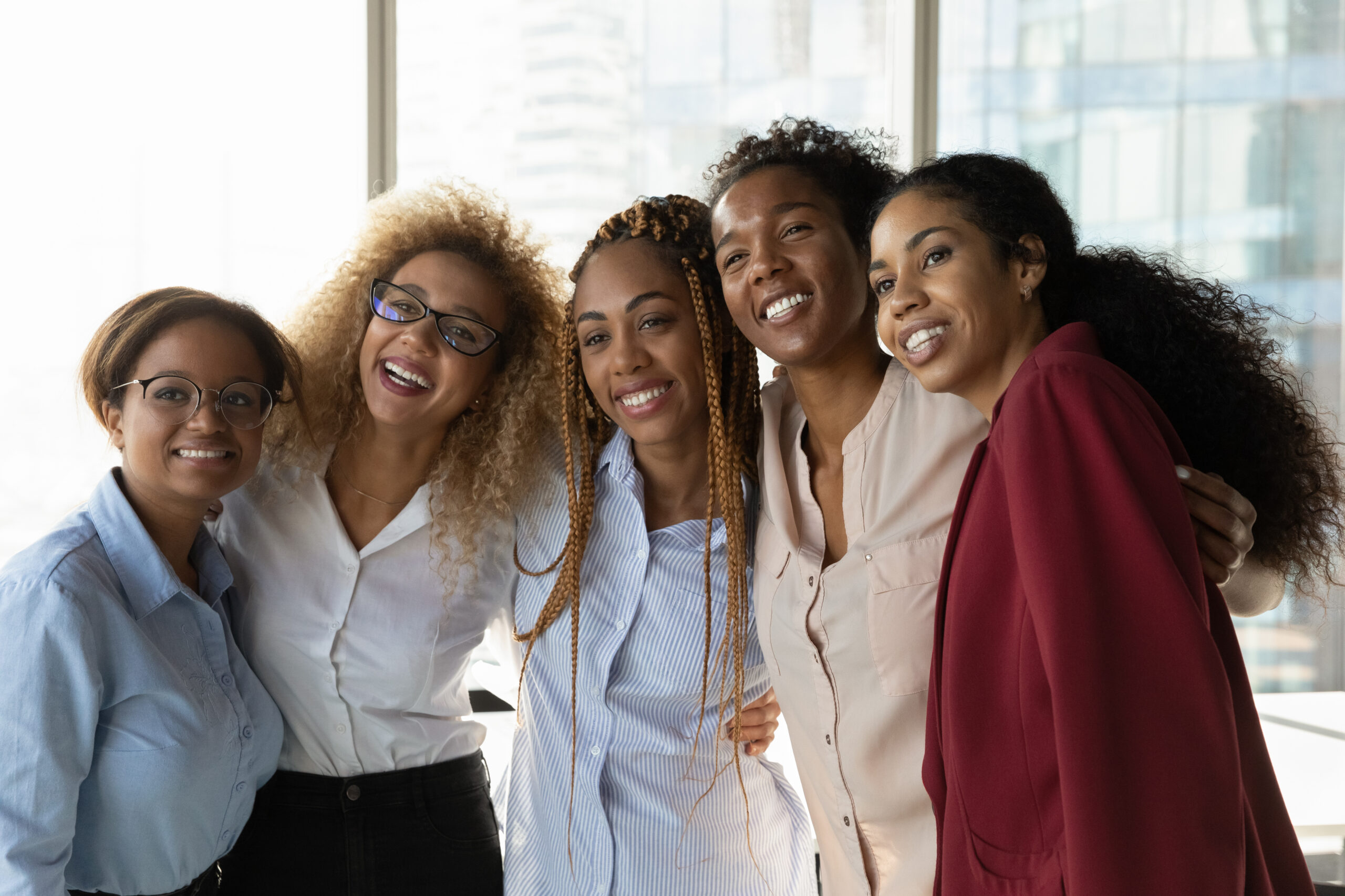 Overjoyed multiethnic diverse female colleagues hug pose for team self-portrait picture together in office.